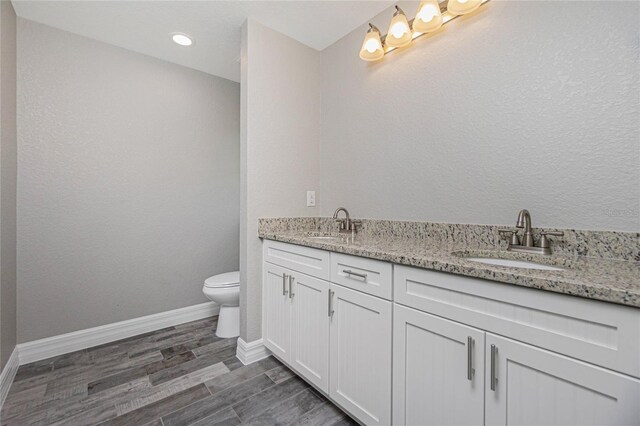 bathroom with double sink vanity, toilet, and hardwood / wood-style floors