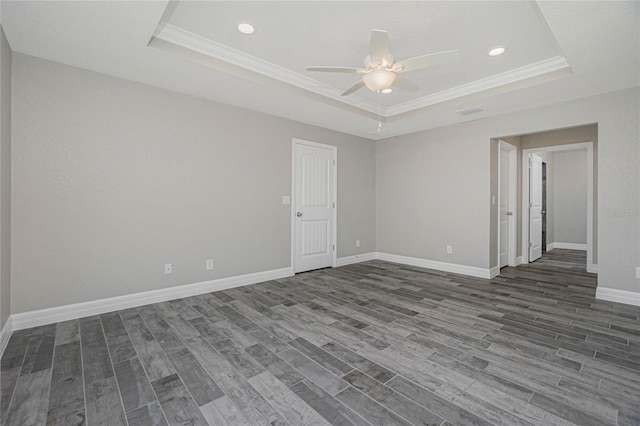 empty room with ceiling fan, crown molding, dark hardwood / wood-style flooring, and a raised ceiling