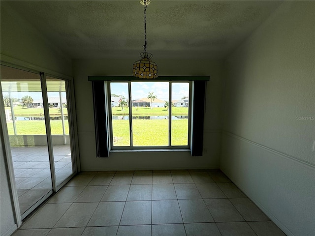 unfurnished dining area with light tile patterned floors, a textured ceiling, and a wealth of natural light