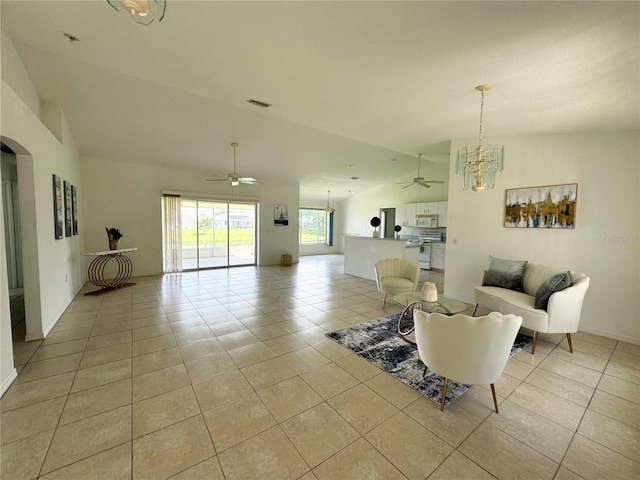 tiled living room with ceiling fan with notable chandelier and vaulted ceiling