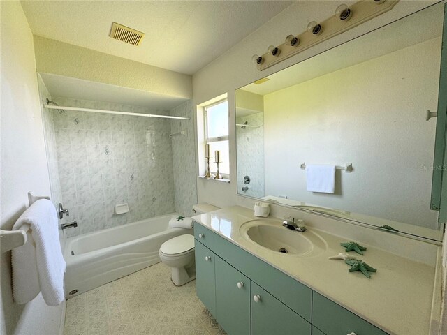 full bathroom with vanity, tile patterned flooring, a textured ceiling, tiled shower / bath, and toilet