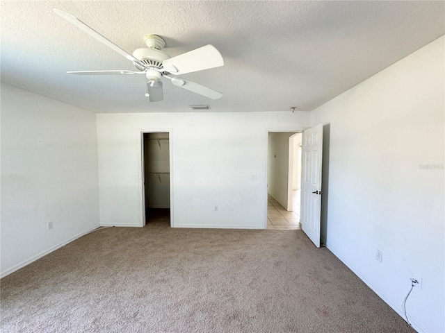 unfurnished bedroom with a closet, visible vents, a ceiling fan, light carpet, and a textured ceiling