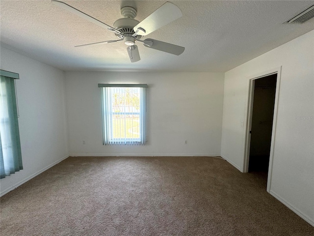 carpeted empty room featuring a ceiling fan, visible vents, a textured ceiling, and baseboards