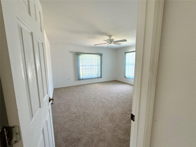 carpeted spare room featuring a textured ceiling and ceiling fan