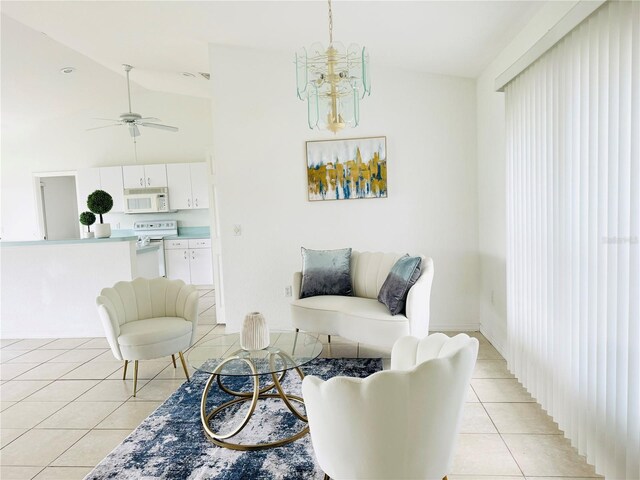 living room with lofted ceiling, ceiling fan with notable chandelier, and light tile patterned flooring