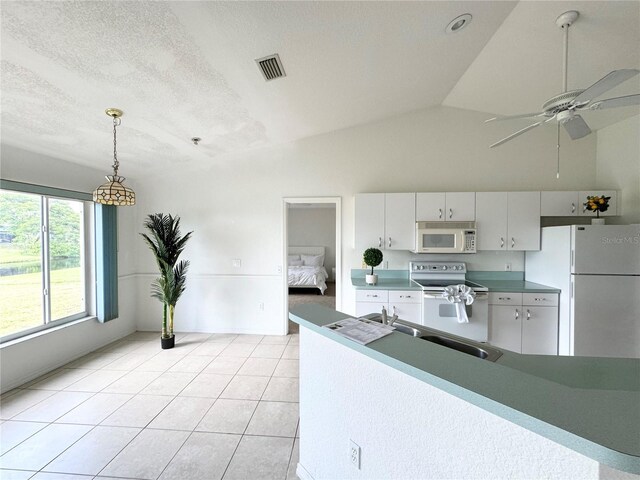 kitchen with white cabinetry, light tile patterned floors, white appliances, vaulted ceiling, and hanging light fixtures