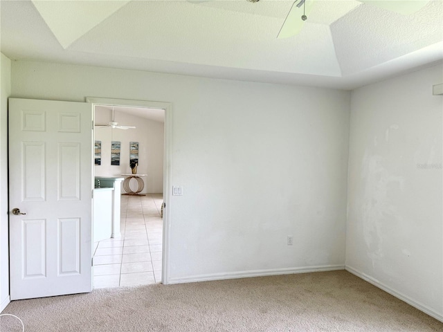 unfurnished room featuring ceiling fan, light tile patterned floors, a textured ceiling, light colored carpet, and vaulted ceiling