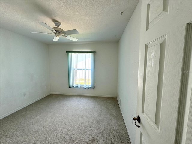 empty room featuring ceiling fan, baseboards, a textured ceiling, and light colored carpet