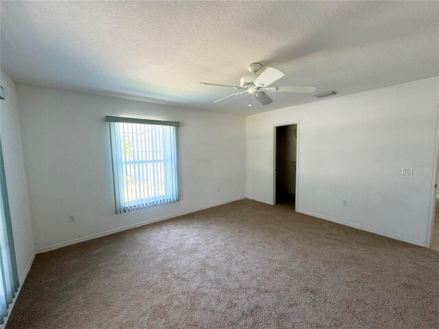 carpeted empty room featuring ceiling fan and a textured ceiling