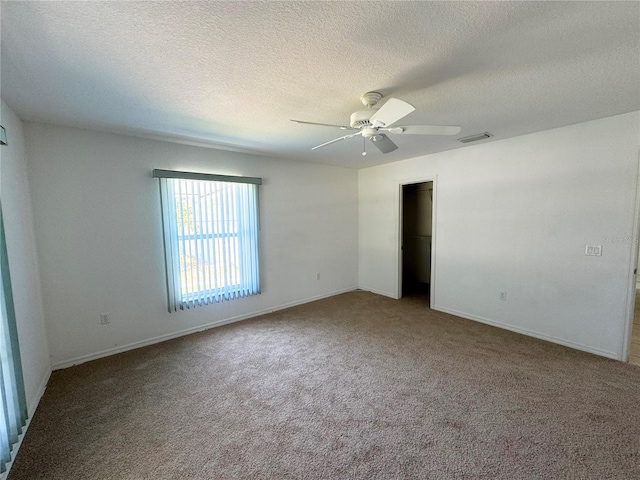 carpeted spare room featuring baseboards, a textured ceiling, visible vents, and a ceiling fan