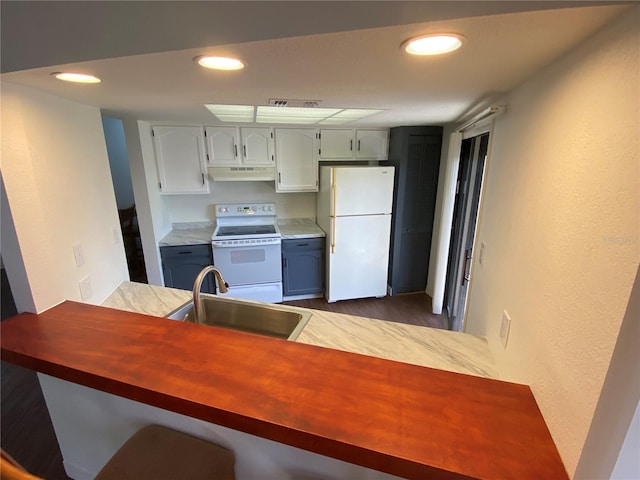 kitchen featuring hardwood / wood-style floors, sink, white cabinets, white appliances, and a breakfast bar