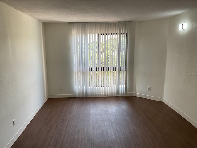 spare room with dark hardwood / wood-style flooring and a textured ceiling