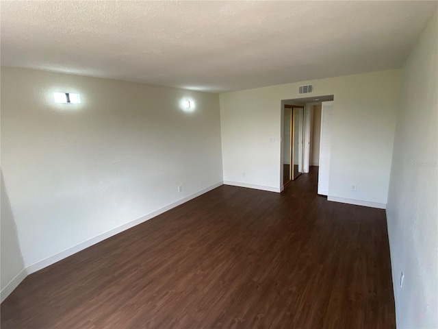 unfurnished room with dark wood-type flooring and a textured ceiling