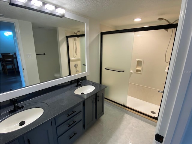 bathroom with an enclosed shower, toilet, dual bowl vanity, and tile patterned flooring