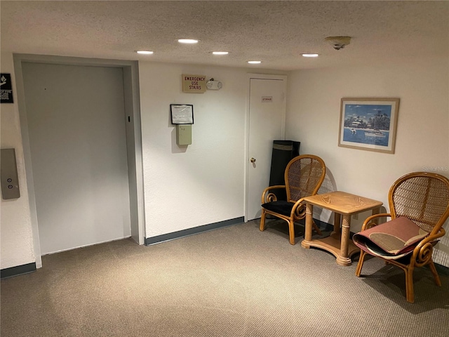 sitting room with a textured ceiling, carpet, and elevator