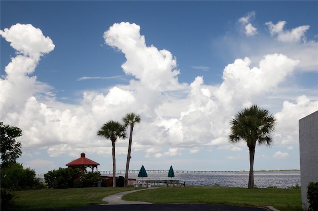 view of home's community with a gazebo, a water view, and a lawn