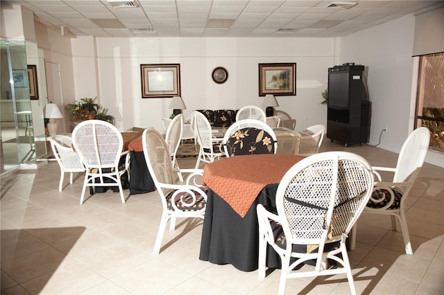 dining area with light tile patterned flooring and a paneled ceiling