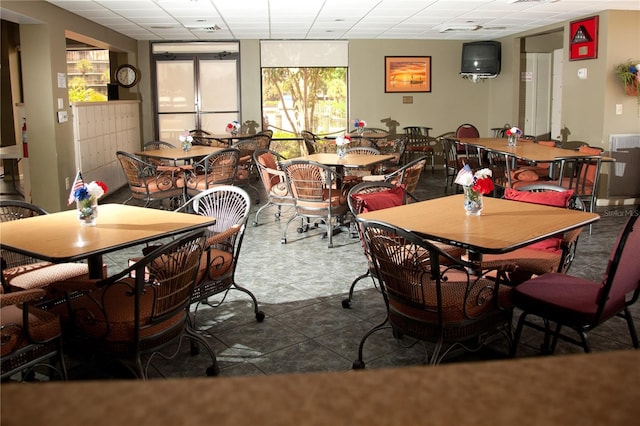 dining area with a drop ceiling and tile patterned flooring