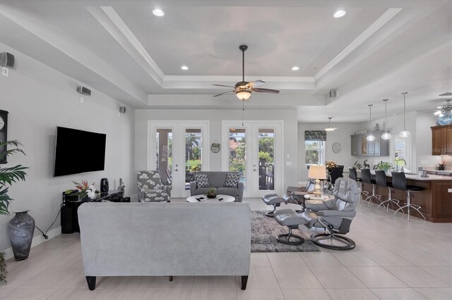 tiled living room with a tray ceiling, ceiling fan, and french doors