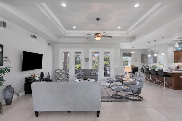 living area with a tray ceiling, french doors, light tile patterned flooring, and crown molding