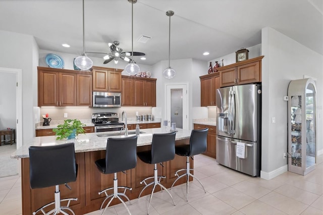 kitchen featuring a kitchen island with sink, tasteful backsplash, appliances with stainless steel finishes, and pendant lighting