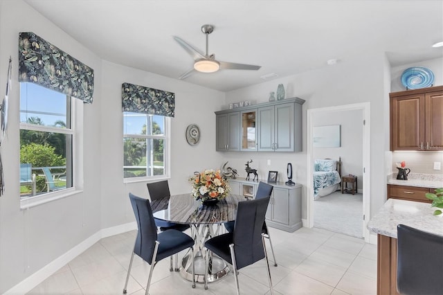 dining space with ceiling fan, baseboards, and light tile patterned flooring