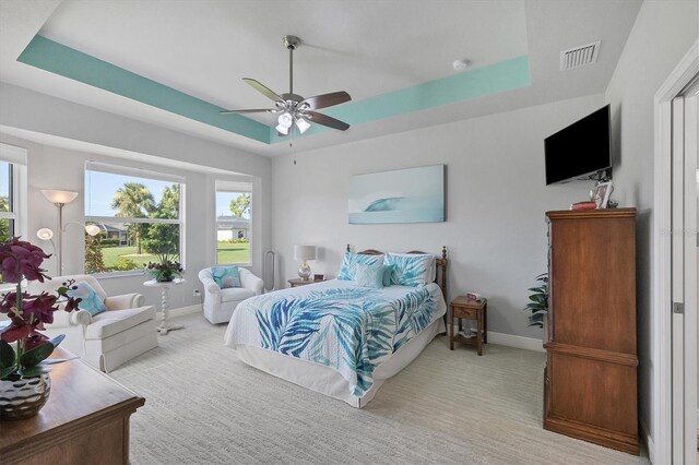 carpeted bedroom featuring ceiling fan and a raised ceiling