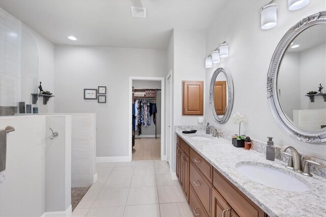 bathroom featuring a spacious closet, double vanity, a sink, and tile patterned floors