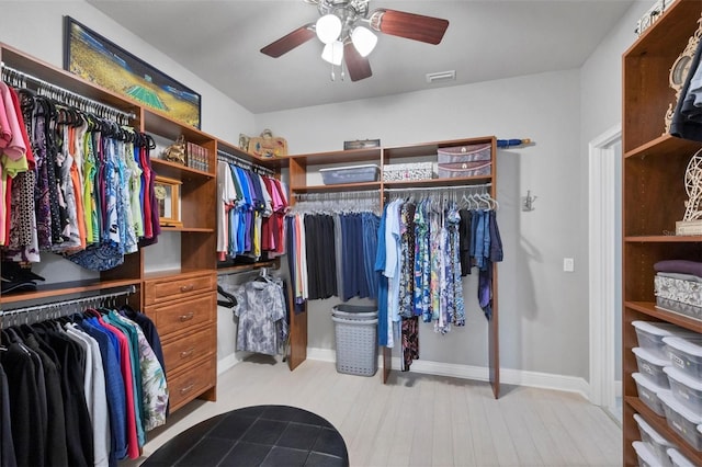 spacious closet with light wood finished floors, visible vents, and a ceiling fan