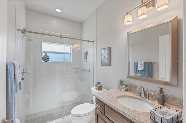 bathroom featuring a shower stall, vanity, and toilet