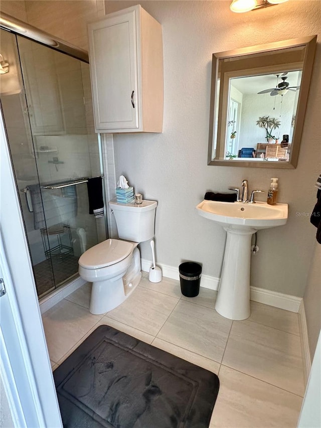 bathroom featuring ceiling fan, toilet, a shower with door, and tile patterned floors