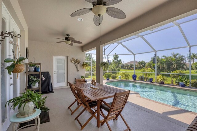 view of swimming pool with glass enclosure, ceiling fan, and a patio