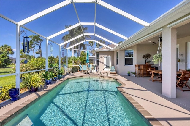 pool with ceiling fan, glass enclosure, outdoor dining space, and a patio area