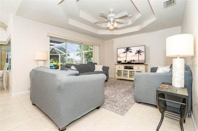 living room with ceiling fan, light tile patterned flooring, and a tray ceiling