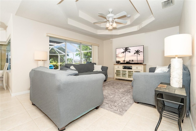 living room featuring a raised ceiling, visible vents, ceiling fan, and light tile patterned floors