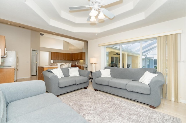 living room featuring ceiling fan, light tile patterned floors, and a tray ceiling