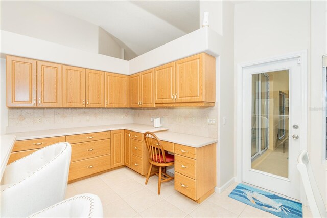 kitchen featuring built in desk, high vaulted ceiling, light tile patterned flooring, and tasteful backsplash