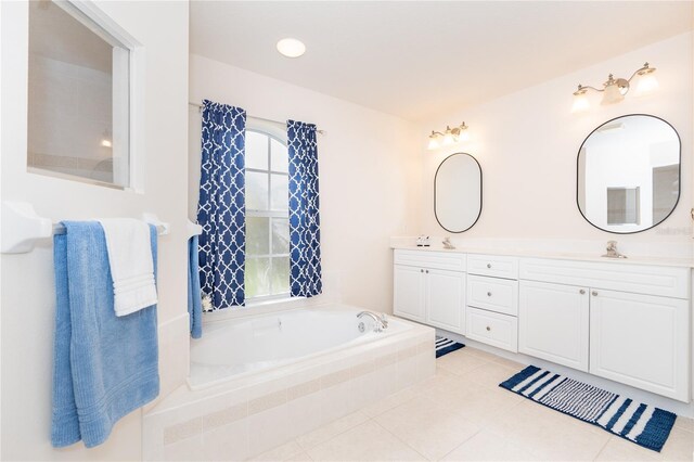 bathroom with tiled bath, double sink vanity, and tile patterned floors