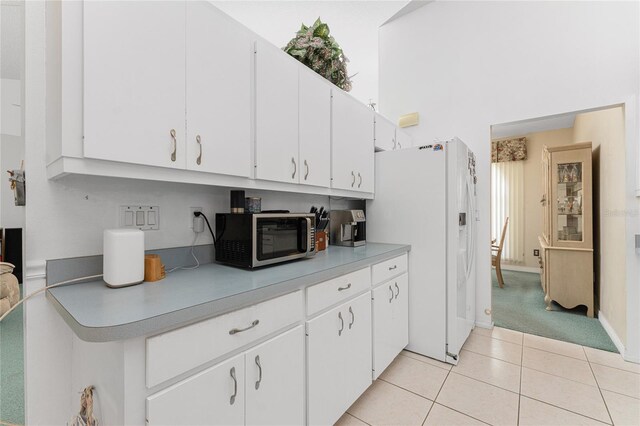 kitchen with white fridge with ice dispenser, white cabinets, and light carpet