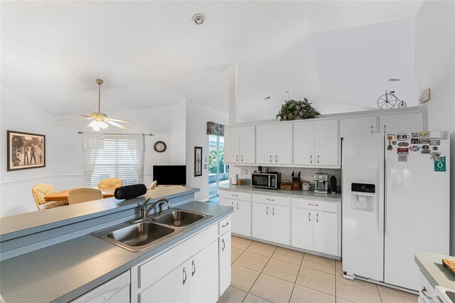 kitchen with sink, white refrigerator with ice dispenser, white cabinets, ceiling fan, and lofted ceiling