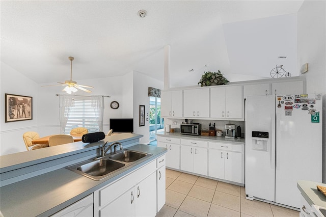 kitchen featuring white fridge with ice dispenser, stainless steel microwave, a sink, and white cabinets