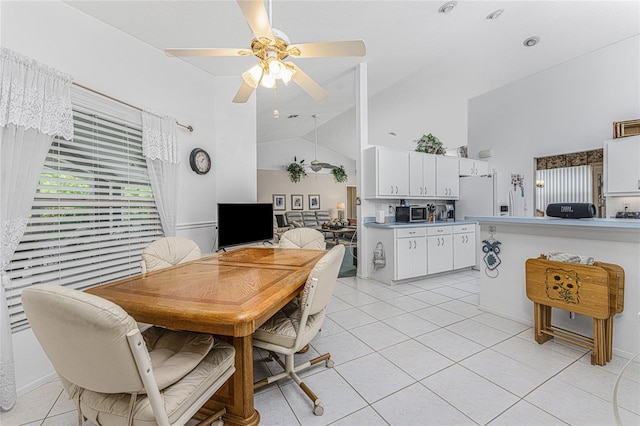 dining space with ceiling fan, high vaulted ceiling, and light tile patterned flooring