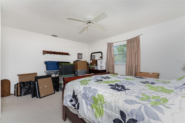 bedroom with a textured ceiling, ceiling fan, and light colored carpet