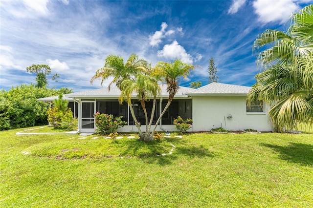 back of property featuring a sunroom, a lawn, and stucco siding