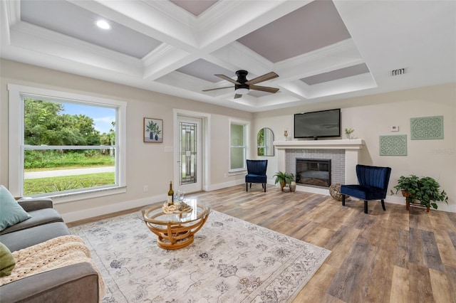 living room with coffered ceiling, a brick fireplace, ceiling fan, beamed ceiling, and wood-type flooring