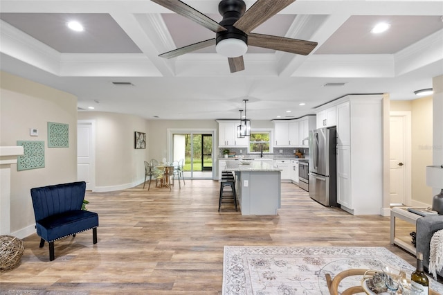 living room with light hardwood / wood-style floors, crown molding, and coffered ceiling