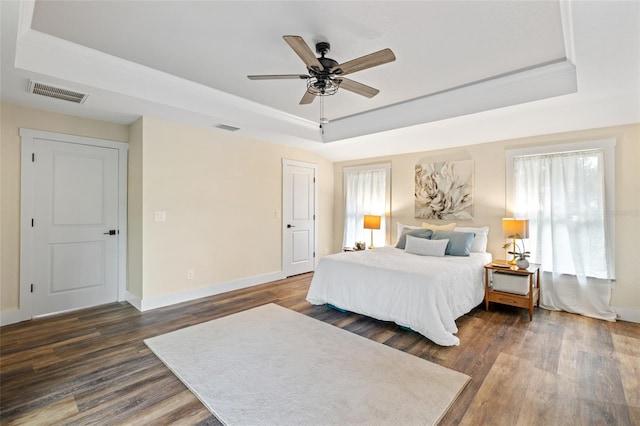 bedroom with ornamental molding, a raised ceiling, ceiling fan, and dark wood-type flooring