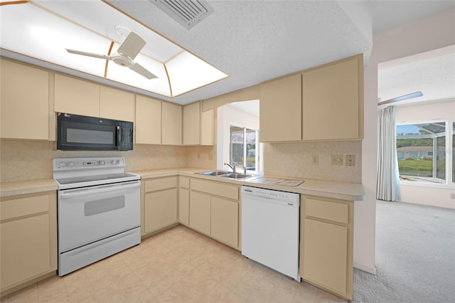 kitchen with cream cabinets, white appliances, a sink, visible vents, and light countertops