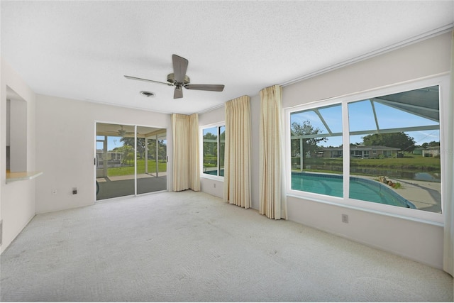 unfurnished room featuring a textured ceiling, ceiling fan, light carpet, a water view, and visible vents