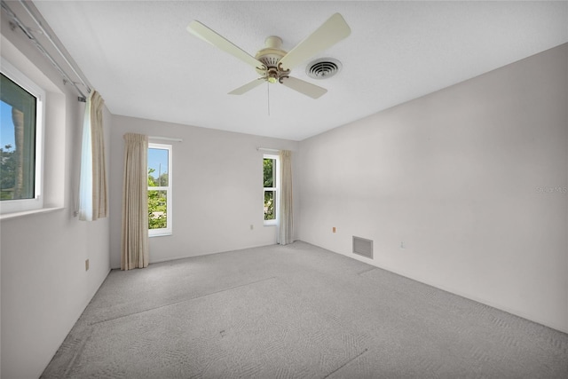 spare room with light colored carpet, visible vents, and ceiling fan